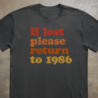 Black t-shirt with 'If lost please return to 1986' text in red and yellow on a textured surface.